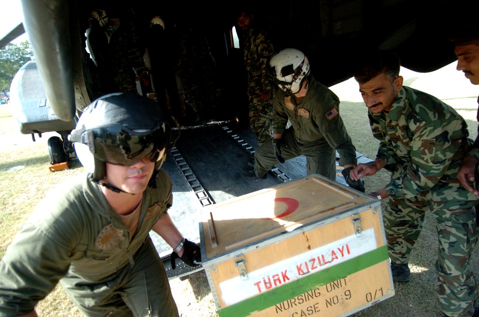 US Navy 051014-N-8796S-105 A U.S. Navy air crewman and a Pakistani soldier carry medical supplies off of a U.S. Navy MH-53E Sea Stallion helicopter in Muzafarabad, Pakistan