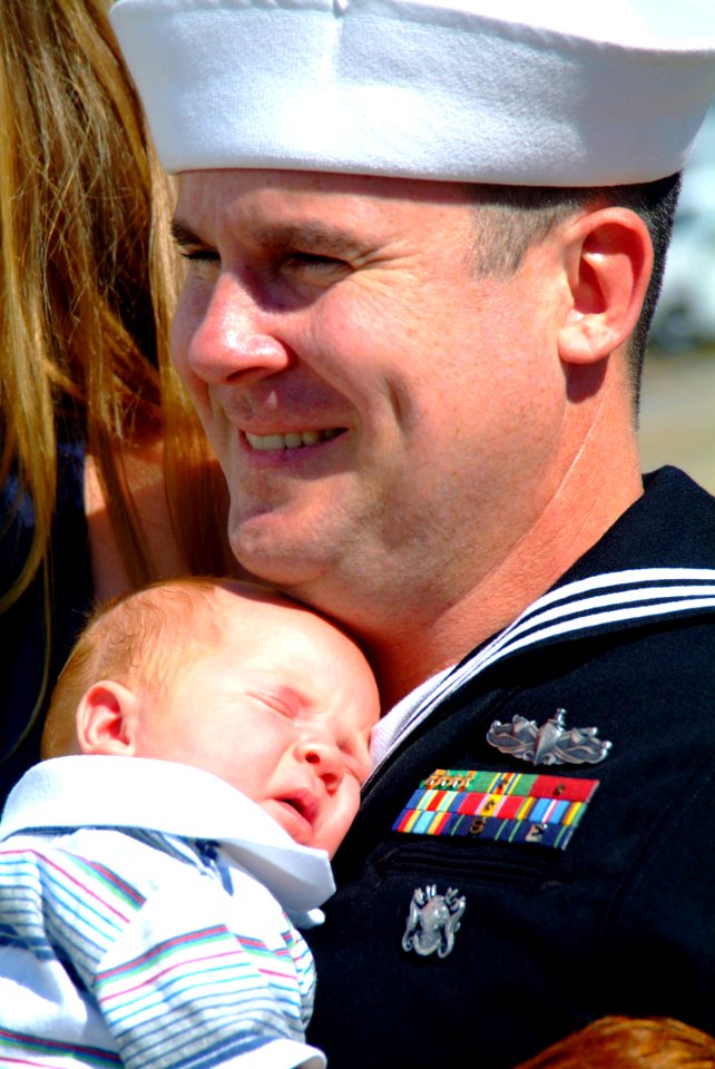 US Navy 051016-N-4772B-071 Hospital Corpsman 1st Class Randle Groves holds his 8-week old daughter on the pier as the rescue and salvage ship USS Safeguard (ARS 50) returns to Sasebo, Japan