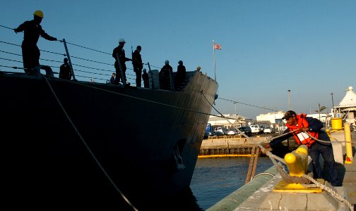 US Navy 051104-N-9866B-018 Sailors aboard the guided missile frigate USS Curts (FFG 38) wait while a line handler assigned to the amphibious assault ship USS Peleliu (LHA 5) ties up a line