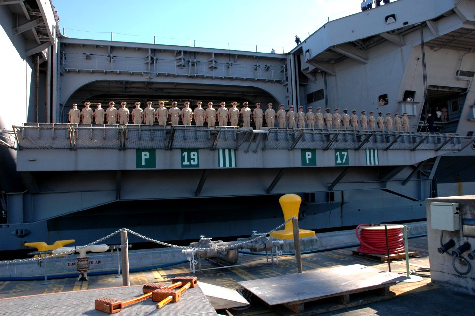 US Navy 050926-N-3390M-070 Newly promoted chief petty officers stand at attention as they sing Anchors Aweigh on one of the four aircraft elevators aboard the Nimitz-class aircraft carrier USS Abraham Lincoln (CVN 72)