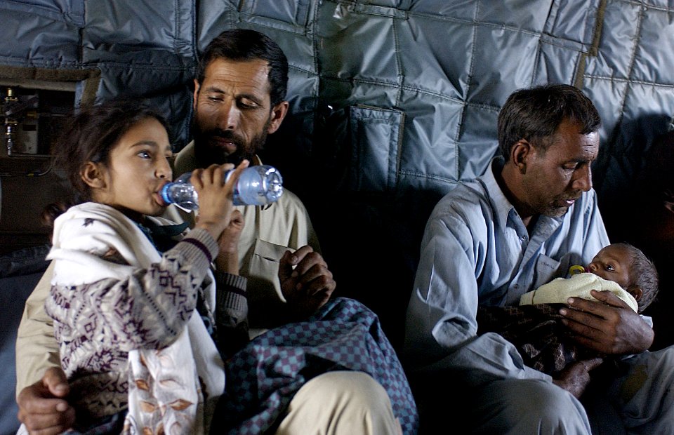US Navy 051021-F-9085B-119 Pakistani men comfort injured children being transported to Islamabad aboard a U.S. Navy MH-53 Sea Dragon helicopter
