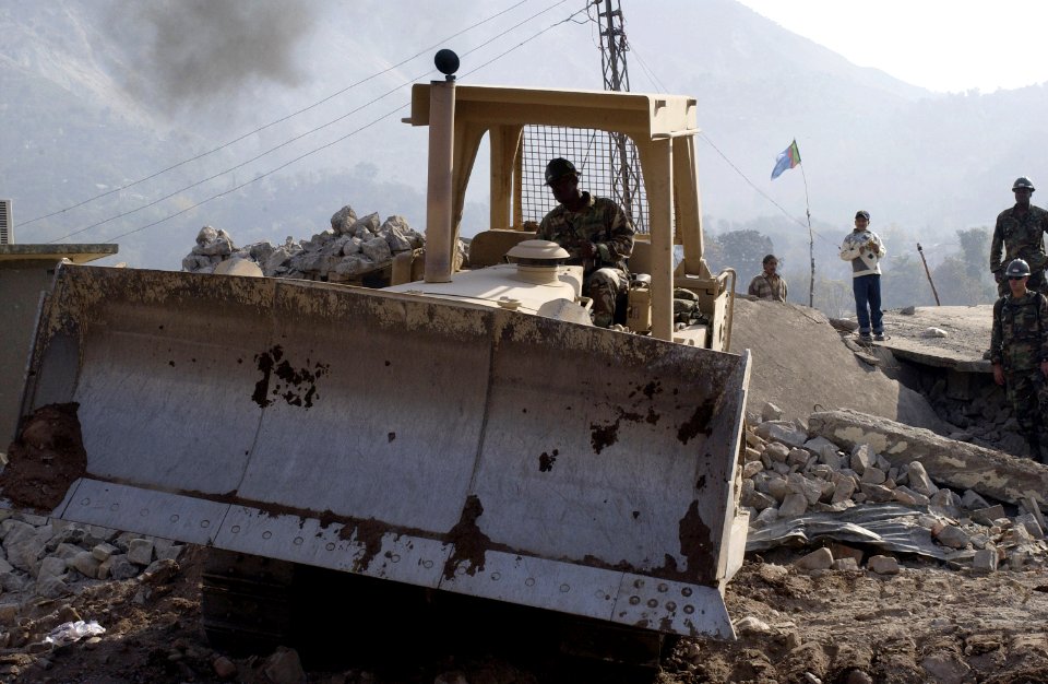 US Navy 051107-F-2729L-004 U.S. Navy Equipment Operator 2nd Class Percy Evans, assigned to Naval Mobile Construction Battalion Seven Four (NMCB-74), removes debris from the fallen Government Girls High School at the Dewan Tent