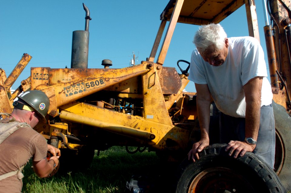 US Navy 050928-N-2653P-061 Hospital Corpsman 1st Class Joshua Ross helps Plaquemines Parish resident change a tire on his bulldozer
