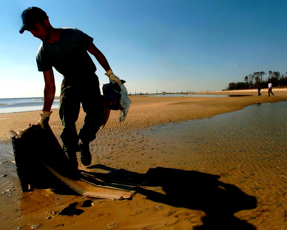 US Navy 051025-N-3729H-065 Electricians Mate 2nd Class Audie Martin, assigned to the Nimitz-class aircraft carrier USS John C. Stennis (CVN 74), gathers debris on a beach in Waveland, Miss