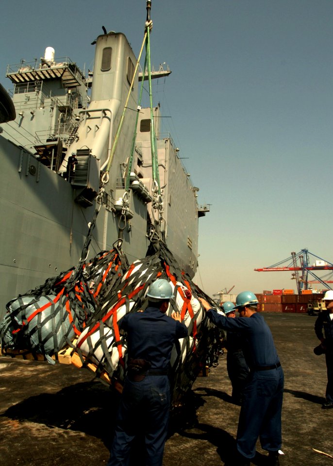 US Navy 051024-N-0716S-006 U.S. Navy Sailors assigned to the dock landing ship USS Pearl Harbor (LSD 52), help guide a load of relief supplies craned down from the boat deck of the ship onto the pier in Karachi, Pakistan