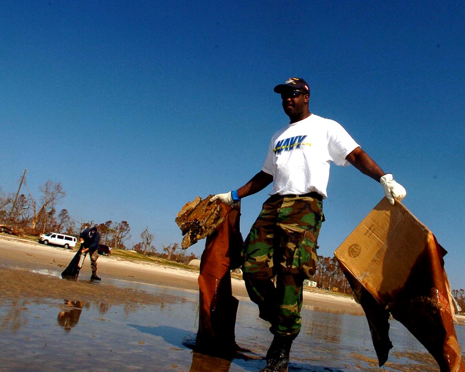 US Navy 051025-N-3729H-067 Electricians Mate 1st Class Christopher Beverly, assigned to the Nimitz-class aircraft carrier USS John C. Stennis (CVN 74), gathers debris on a beach in Waveland, Miss