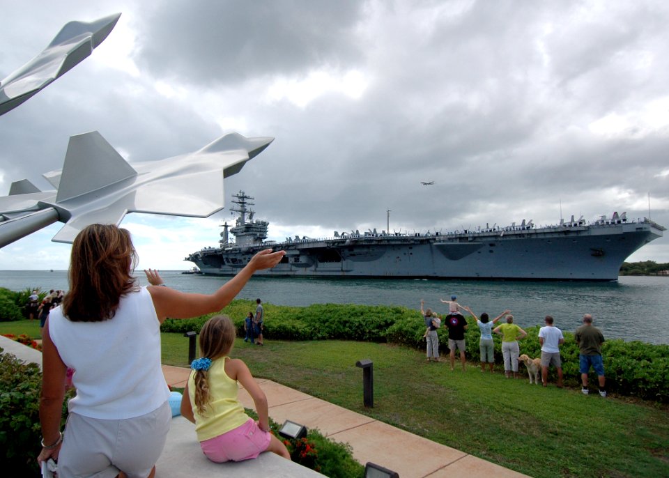 US Navy 051030-N-3019M-002 Family members wave to the nuclear-powered aircraft carrier USS Nimitz (CVN 68) as she passes the missing man memorial on board Hickam Air Force Base, and enters Pearl Harbor