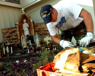 US Navy 051020-N-3729H-122 U.S. Navy Fireman Rob Pysher, assigned to the Nimitz-class aircraft carrier USS John C. Stennis (CVN 74), searches through debris to find religious statues not destroyed by Hurricane Katrina