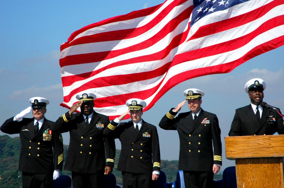 US Navy 051013-N-6106R-010 Chief Aviation Boatswain's Mate Michael Berry, far left, and members of the official party salute as the national anthem is sung during Berry's retirement ceremony