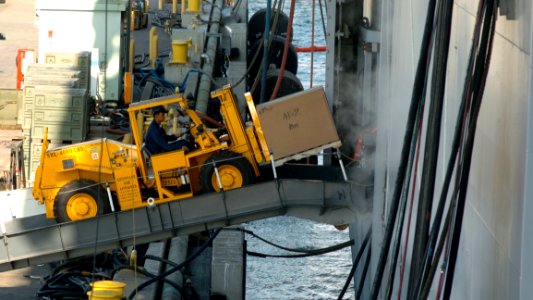 US Navy 051104-N-9866B-003 A Sailor drives his forklift loaded with cargo onto the amphibious assault ship USS Peleliu (LHA 5)