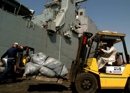 US Navy 051024-N-0716S-007 A U.S. Navy chief petty officer, left, assigned to the dock landing ship USS Pearl Harbor (LSD 52), guides a Pakistani forklift operator as he transports a load of relief supplies on the pier in Kara