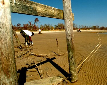 US Navy 051025-N-3729H-092 Electricians Mate 1st Class Christopher Beverly, assigned to the Nimitz-class aircraft carrier USS John C. Stennis (CVN 74), gathers debris on a beach in Waveland, Miss