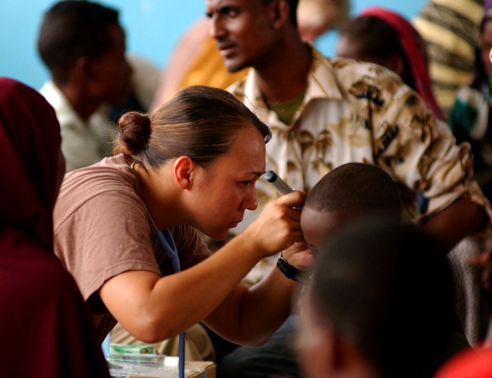 US Navy 051109-F-8425S-256 U.S. Navy Hospital Corpsman Miami Gollyhorn looks into the ears of a local child with an otoscope during a medical examination in Gode, Ethiopia