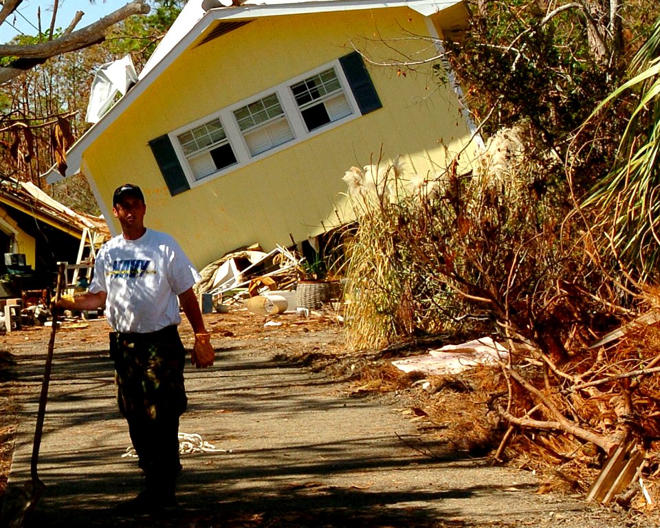 US Navy 051026-N-3729H-102 U.S. Navy Machinist Mate Fireman Andrew Westermire, assigned to the Nimitz-class aircraft carrier USS John C. Stennis (CVN 74), help locals clear their driveway of debris left by Hurricane Katrina