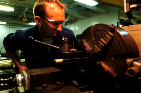 US Navy 051202-N-9866B-009 Machinery Repairman 3rd Class William Peterson, the assistant leading petty officer of the Machine Shop, bores holes for night vision goggle test equipment