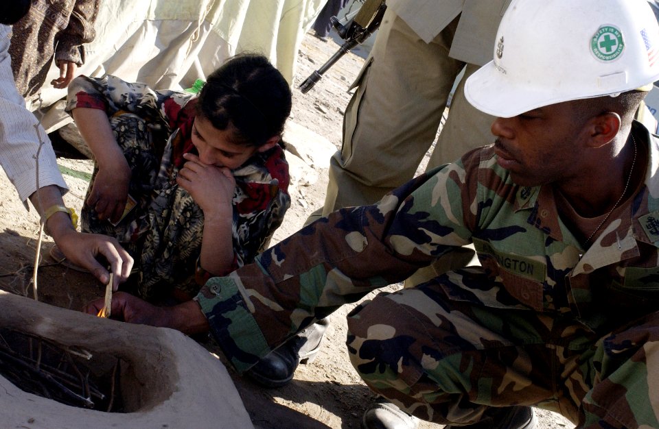 US Navy 051113-F-2729L-010 U.S. Navy Chief Equipment Operator Derrick Arrington, assigned to Naval Mobile Construction Battalion Seven Four (NMCB-74), right, helps a displaced earthquake survivor