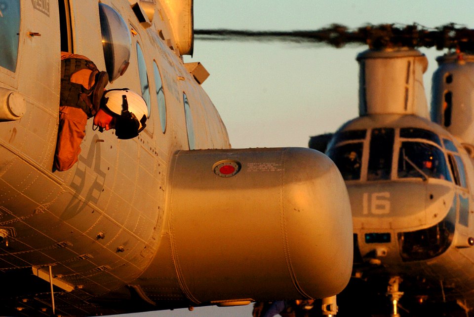 US Navy 051203-N-9866B-344 A crew member of a U.S. Marine Corps CH-46E Sea Knight helicopter looks out the window of his helicopter as it settles on the flight deck for landing