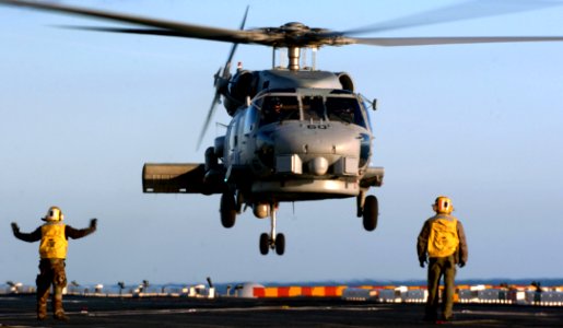 US Navy 051203-N-9866B-247 Aviation Boatswain's Mates direct an SH-60B Seahawk helicopter onto the flight deck of the amphibious assault ship USS Peleliu (LHA 5)