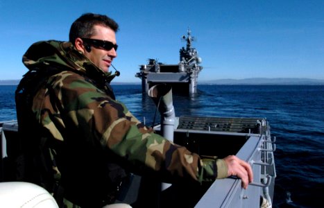 US Navy 051205-N-9866B-068 U.S. Navy Culinary Specialist 1st Class Michael Elliot, the craftmaster of Landing Craft, Utility One Six Six Five (LCU-1665), assigned to Assault Craft Unit One (ACU-1), communicates with his crew in