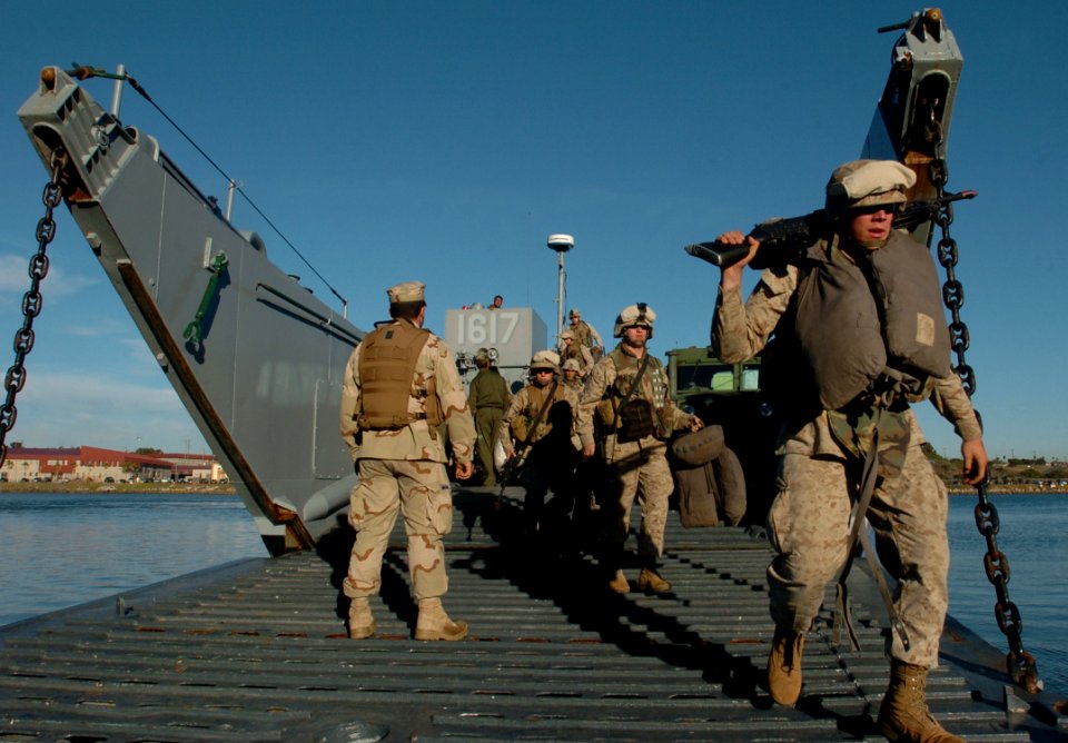 US Navy 051205-N-9866B-297 Construction Mechanic Seaman Bryce Terry, left, assigned to Beach Master Unit, directs Marines assigned to the 11th Marine Expeditionary Unit
