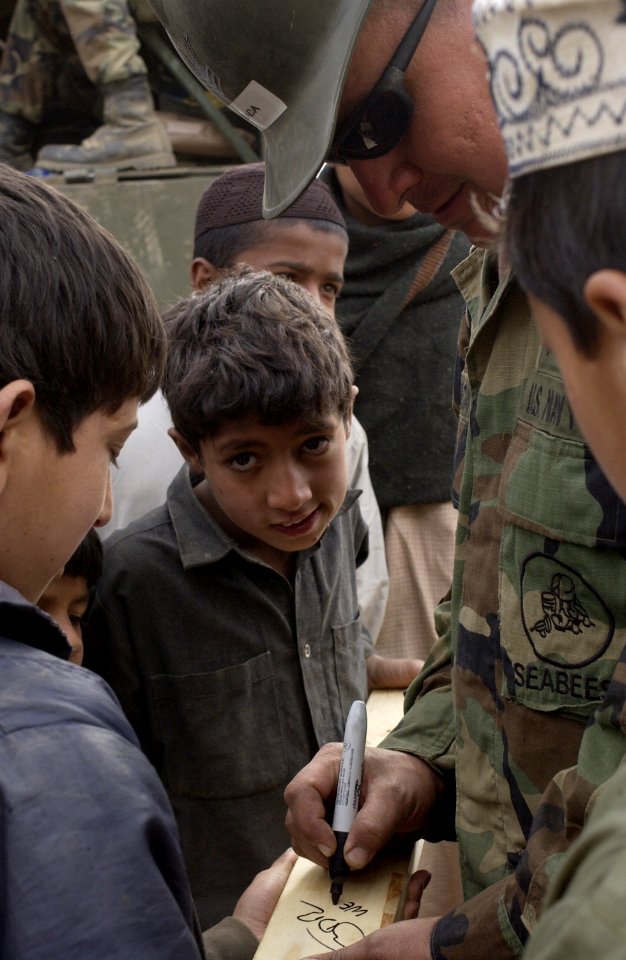 US Navy 051121-F-2729L-004 U.S. Navy 1st Class Manuel Baca, assigned to Naval Mobile Construction Battalion Seven Four (NMCB-74), signs a cricket bat that he made for children at Jabba Farm Tent Village in Shinkiari, Pakistan