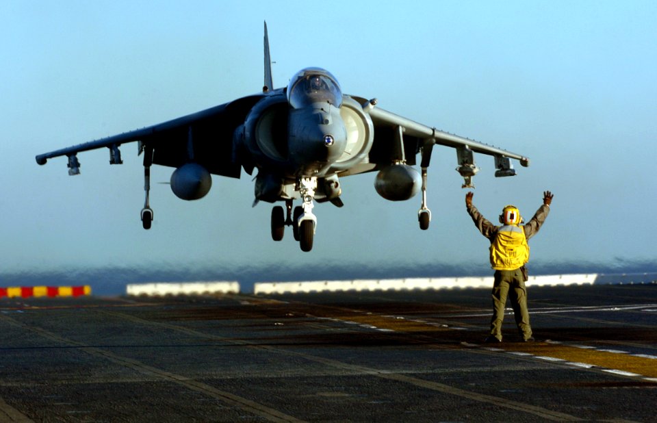 US Navy 051203-N-9866B-072 Aviation Boatswain's Mate 1st Class Roberto Gonzales directs an AV-8B Harrier as it lands on the flight deck of the amphibious assault ship USS Peleliu (LHA 5)