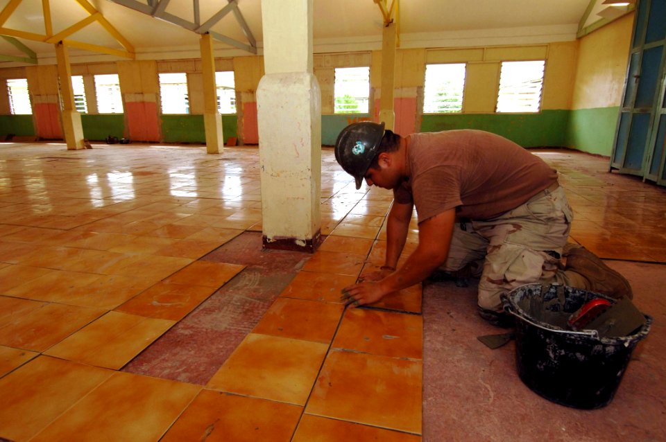 US Navy 051224-N-4374S-002 Builder 3rd Class Jonathan Martinez, assigned to Naval Mobile Construction Battalion Three (NMCB-3), applies a ceramic floor tile during the restoration project at the Providence Hall in St. Elisabet