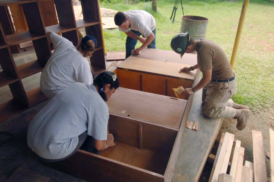 US Navy 051226-N-4374S-013 Sailors assigned to the guided missile destroyer USS Winston S. Churchill (DDG 81) assist with refurbishing old wooden cabinets