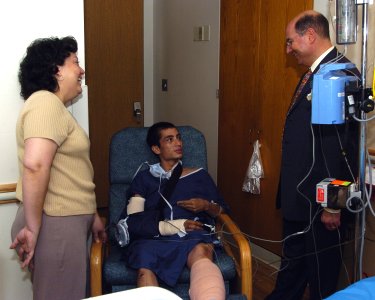 US Navy 060104-N-2568S-002 Secretary of the Navy, the Honorable Dr. Donald Winter meets with Lance Cpl. Martin Roman and his mother, during a visit to see the wounded Sailors and Marines at National Naval Medical Center photo