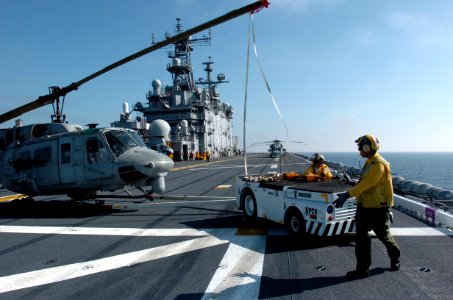 US Navy 051114-N-9866B-055 An Aviation Boatswain's Mate directs the driver of a tow tractor as he backs a U.S. Marine Corps UH-1N Huey helicopter to its parking space