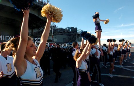 US Navy 051221-N-9866B-001 U.S. Naval Academy cheerleaders show their team's spirit in front of the decommissioned aircraft carrier USS Midway (CV 41)