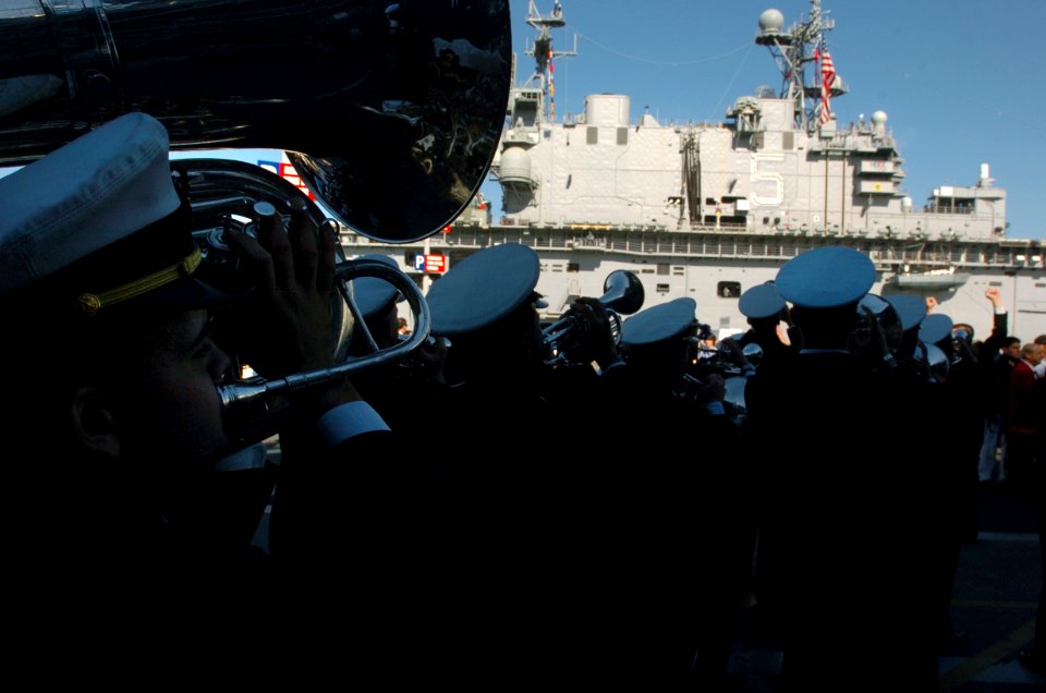 US Navy 051221-N-9866B-139 U.S. Naval Academy Midshipmen Band perform outside the decommissioned aircraft carrier USS Midway (CV 41) in front of the amphibious assault ship USS Peleliu (LHA 5)
