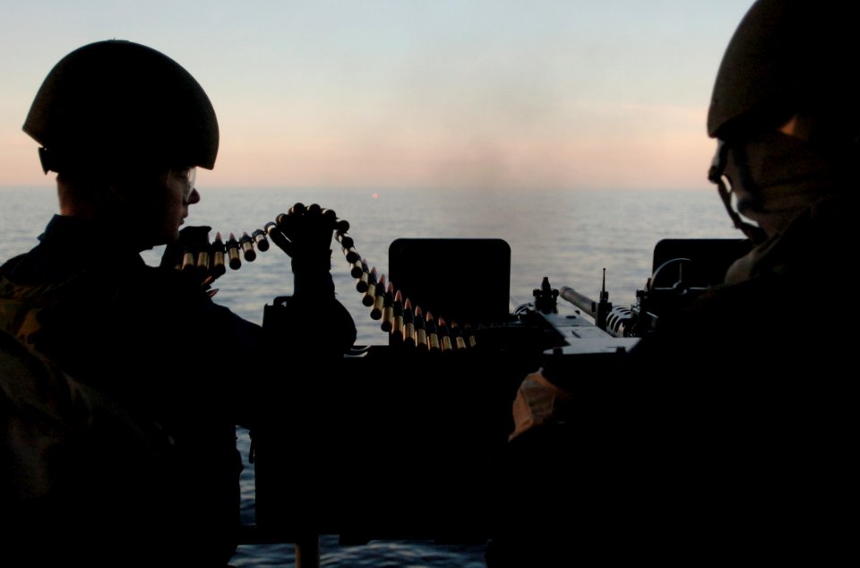 US Navy 060117-N-9866B-281 Gunner's Mate 3rd Class Sergey Ivanshenko feeds 50 cal. rounds for his for Aviation Ordnanceman 3rd Class Keith Mitchell