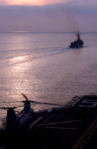 US Navy 051213-N-9866B-005 A CH-46E Sea Knight helicopter prepares to take off from the flight deck of the amphibious assault ship USS Peleliu (LHA 5) with the frigate USS Halsing (FFG 97) sailing in formation