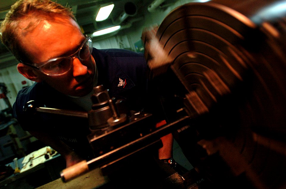 US Navy 051202-N-9866B-006 Machinery Repairman 3rd Class William Peterson, the assistant leading petty officer of the Machine Shop, bores holes for night vision goggle test equipment