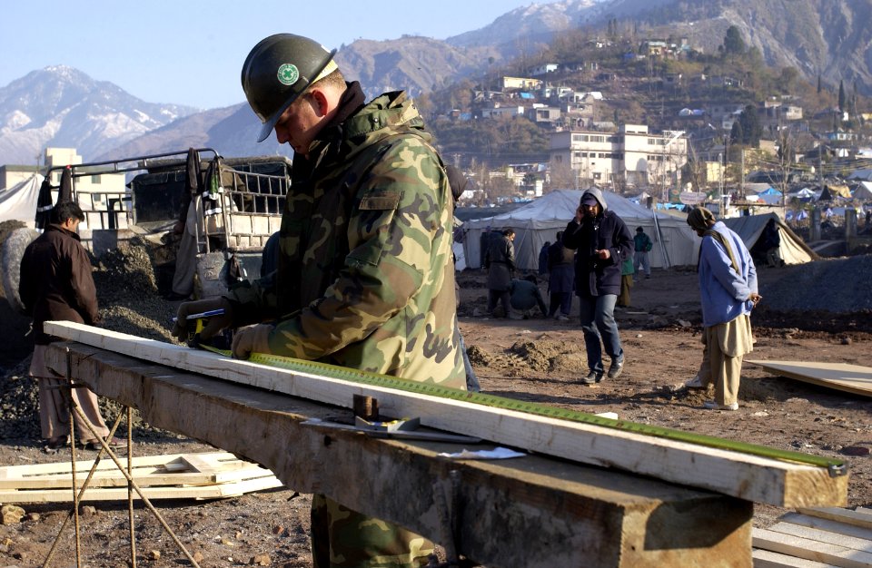 US Navy 060106-F-2729L-012 U.S. Navy Petty Officer 3rd Class Jason Specks assigned to Naval Mobile Construction Battalion Four (NMCB-4) measures wood for a Southeast Asia Hut (SEAHUT)