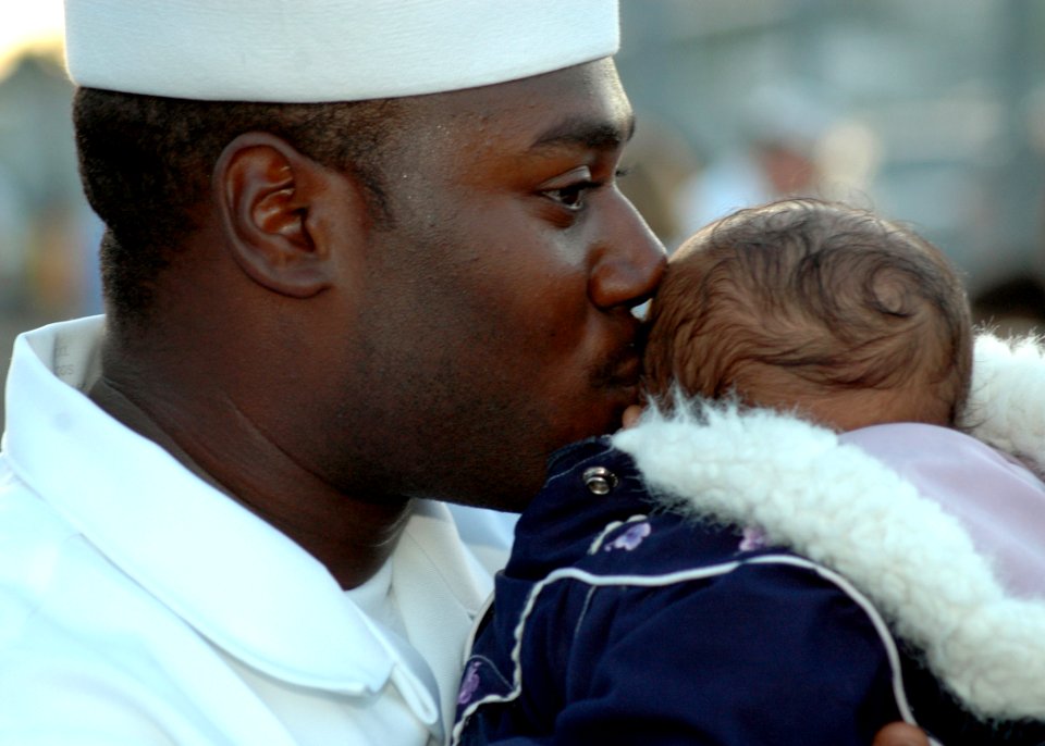 US Navy 060105-N-3019M-002 Boatswain's Mate 3rd Class Leroy Quinn kisses his son on the pier before departing aboard the guided missile destroyer USS Chung-Hoon (DDG 93)