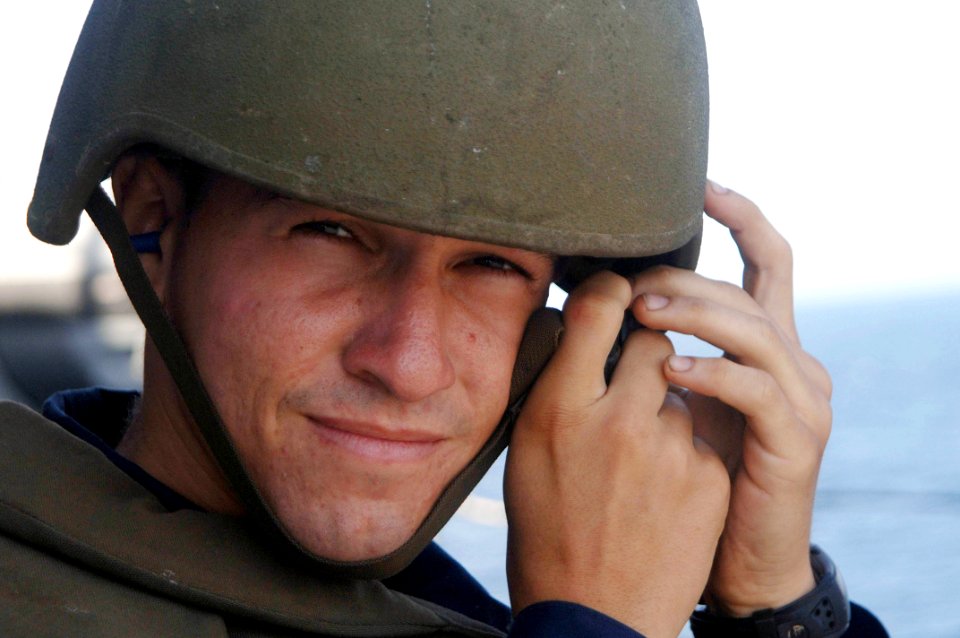 US Navy 060127-N-4374S-007 Seaman Douglas Thomas dons a helmet prior to firing a .50 caliber machine gun during a live fire exercise
