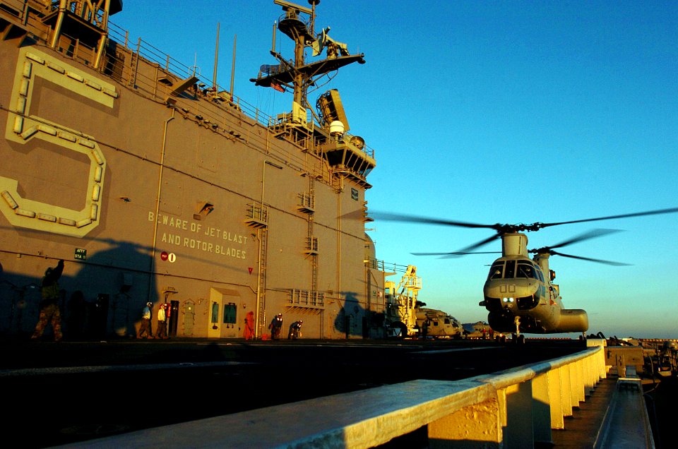 US Navy 051203-N-9866B-328 An Aviation Boatswain's Mate directs a CH-46E Sea Knight helicopter as it lands on the flight deck of the amphibious assault ship USS Peleliu (LHA 5)