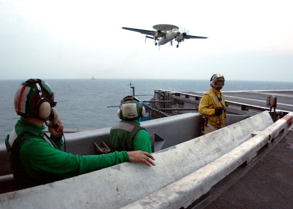 US Navy 060203-N-0685C-001 Flight deck personnel look on as an E-2C Hawkeye prepares for an arrested landing aboard the Nimitz-class aircraft carrier USS Theodore Roosevelt (CVN 71)