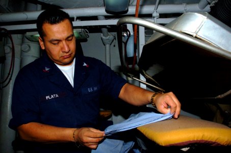 US Navy 060124-N-9866B-006 Ship's Serviceman 2nd Class Gilberto Plata presses a utility uniform in the ship's laundry room