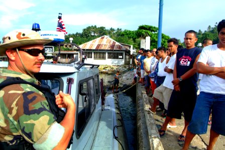 US Navy 060220-N-4772B-436 Hospital Corpsman 2nd Class Leonard Ray talks with local villagers from an 11 meter Rigid Hull Inflatable Boat (RHIB) deployed from the dock landing ship USS Harpers Ferry (LSD 49)