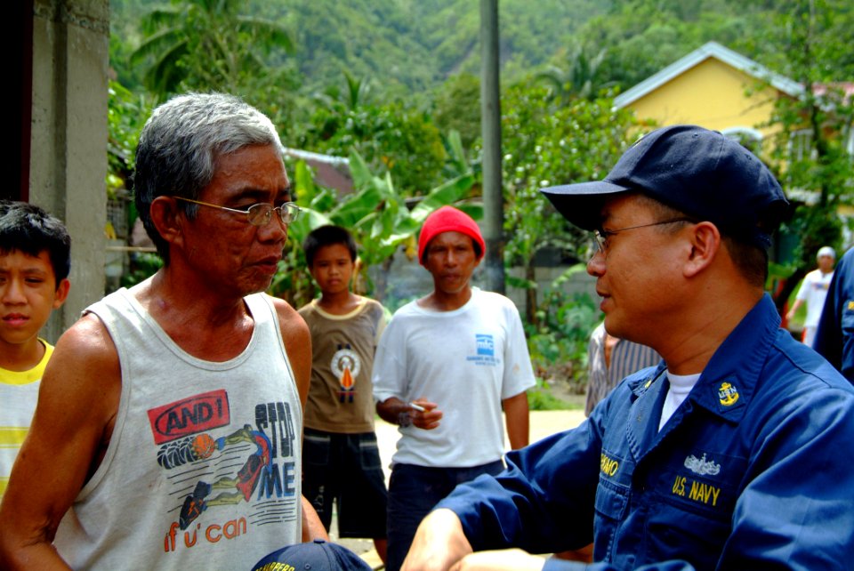 US Navy 060221-N-4772B-037 USS Harpers Ferry (LSD 49), Chief Culinary Specialist Albino Palomo speaks with one of the town elders on the placement of vehicles through the tiny fishing village of Himbangen