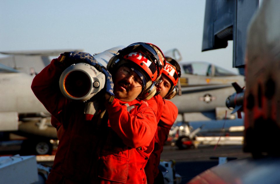 US Navy 060225-N-4776G-136 A team of aviation ordnancemen carry ordnance to a F-A-18C Hornet aboard the Nimitz-class aircraft carrier USS Ronald Reagan (CVN 76)