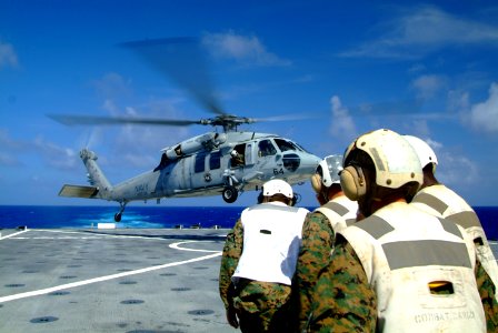 US Navy 060214-N-4772B-014 Combat Cargo Marines brace themselves as an MH-60S Seahawk helicopter lands on the flight deck of the amphibious dock landing ship USS Harper Ferry (LSD 49)