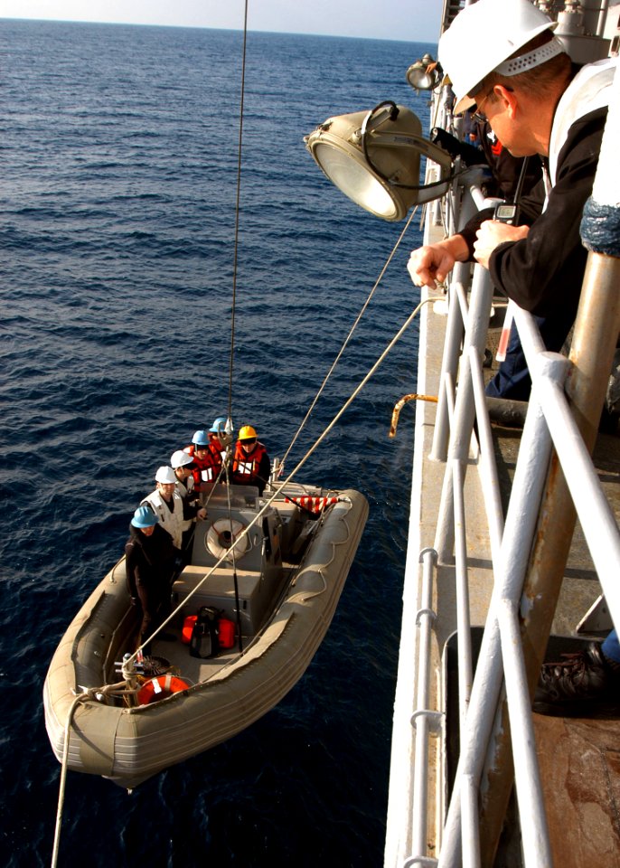 US Navy 060127-N-7526R-038 Small Boat Safety Observer Chief Boatswain's Mate Russell Townsend looks on as a Rigged Haul Inflatable Boat (RHIB) and it's crew are lowered into the water as a safety precaution