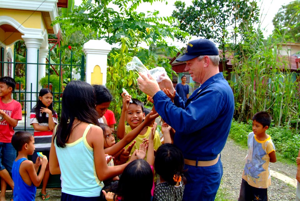 US Navy 060221-N-4772B-153 USS Harpers Ferry (LSD 49), Command Master Chief Darryl Brandt hands out candy to children in the small fishing village of Himbangen