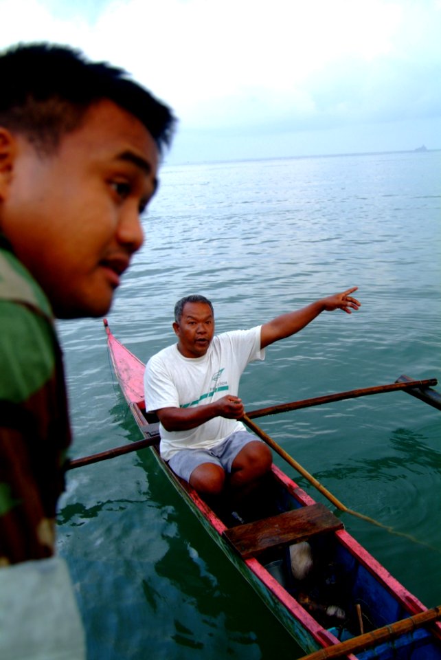 US Navy 060220-N-4772B-595 Electrician's Mate 2nd Class Christopher Arntzen from Assault Craft Unit 1, Detachment Western Pacific, speaks with one of the local fishermen from an 11 meter Rigid Hull Inflatable Boat (RHIB)