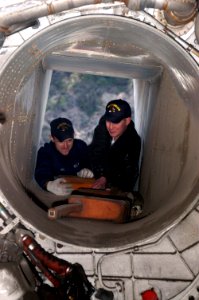 US Navy 060320-N-8854R-021 Aviation Boatswain's Mate Airmen Joshua Baker, and Jared Hash, remove chocks from the intake of an F-14 Tomcat engine compartment