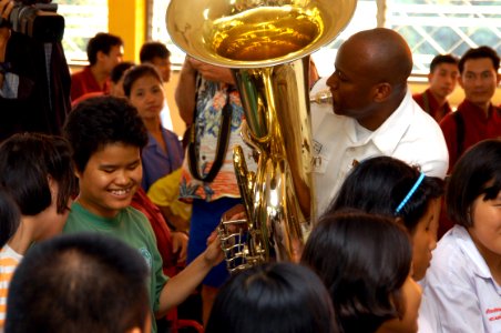 US Navy 060227-N-1194D-004 Musician 2nd Class Algie Smith helps a child operate a tuba during a goodwill concert by the U.S. Seventh Fleet Band at the Pattaya Redemptorist School for the Blind photo